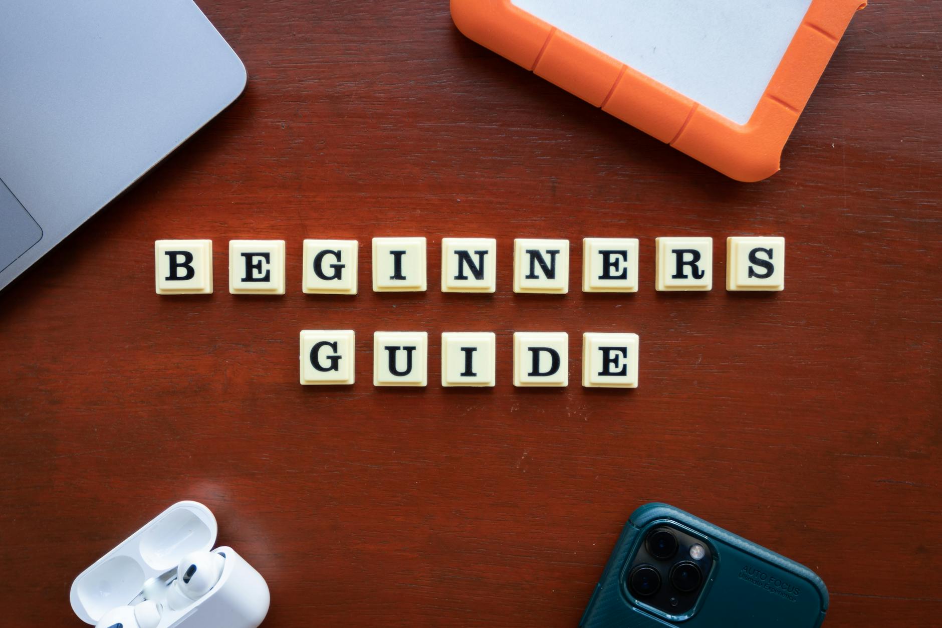 Płaskie ujęcie gadżetów i napisu Beginners Guide na drewnianym biurku