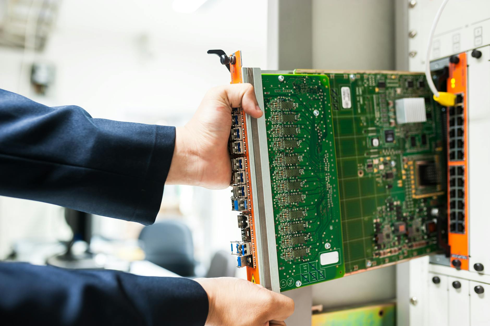 Technik wkłada płytę PLC do szafy sieciowej w zakładzie przemysłowym