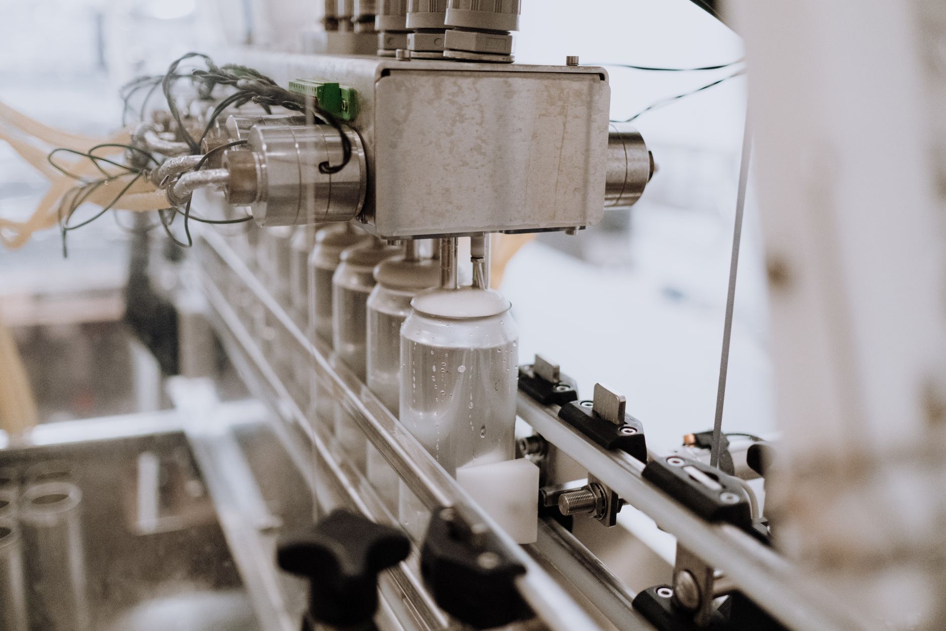 Zbliżenie automatycznej maszyny do napełniania puszek na linii produkcyjnej