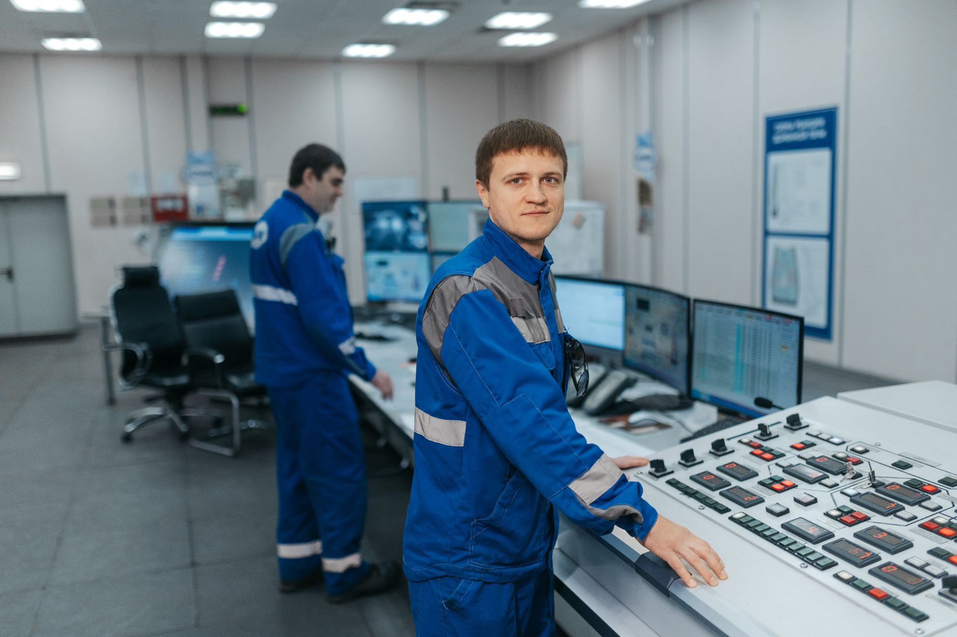 Dwóch techników obsługuje maszyny w nowoczesnej sterowni przemysłowej