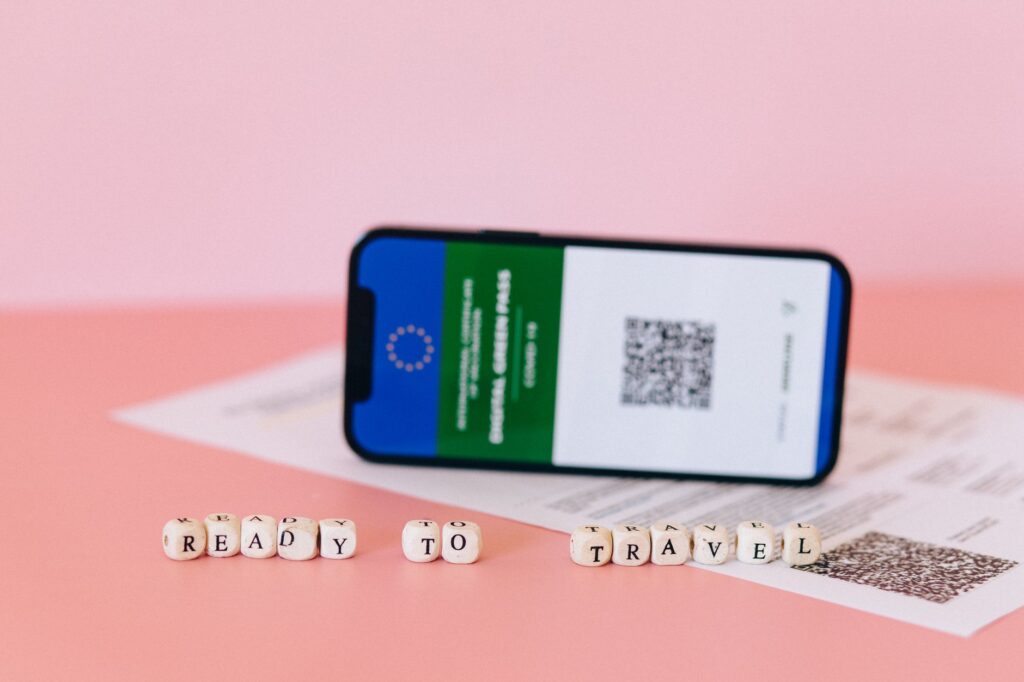 Smartfon z cyfrowym kodem na różowym tle z koralikami podróżnymi